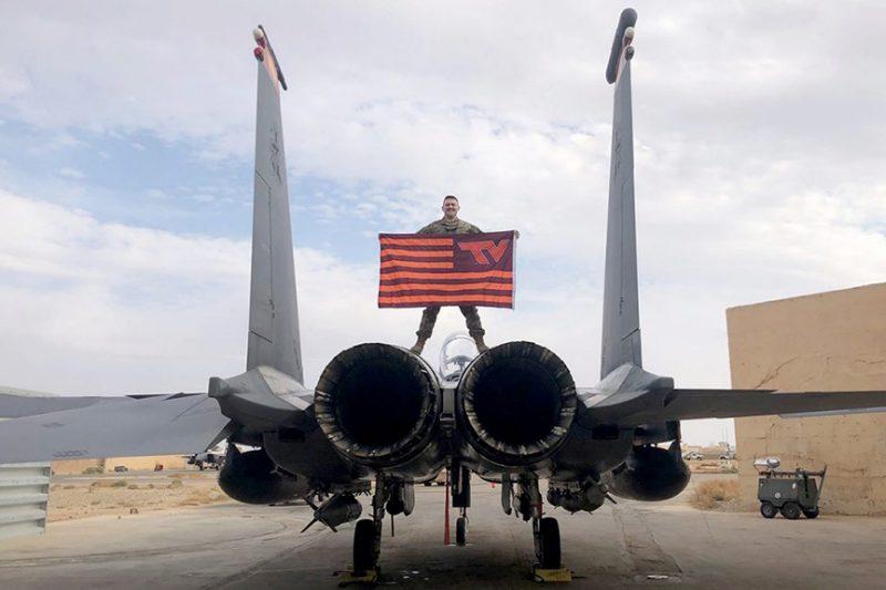 一个军团的校友站在飞机上举着弗吉尼亚理工大学的旗帜.